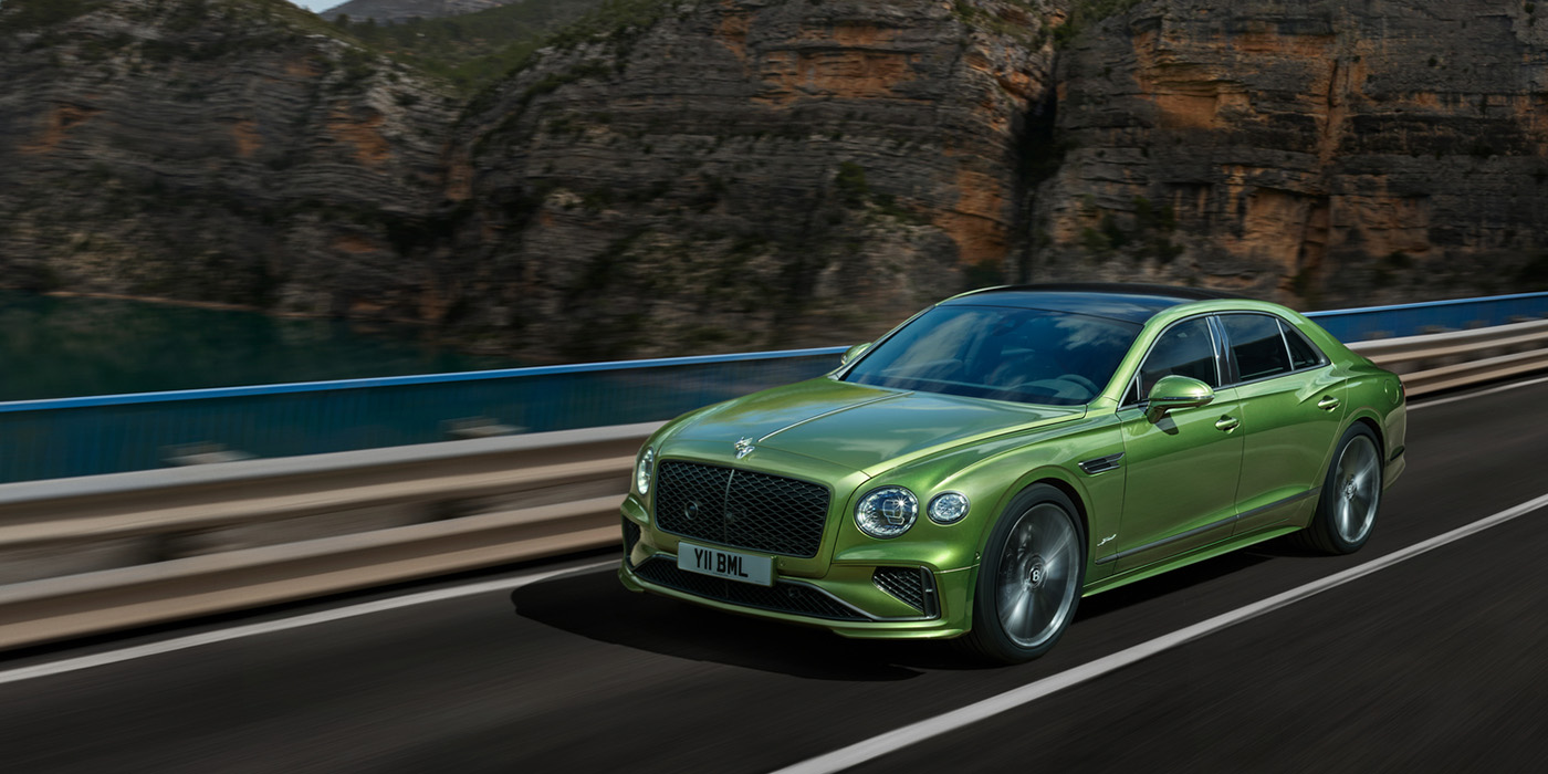Bentley Monaco Bentley New Flying Spur Speed v8 hybrid sedan driving dynamically on a mountain road in Tourmaline Green paint