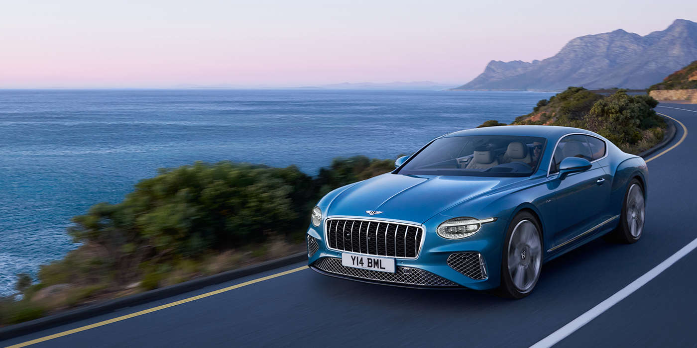 Bentley Monaco New Bentley Continental GT Azure coupe in Light Windsor blue paint with 22 inch Azure wheels and chrome grill, driving dynamically by the sea