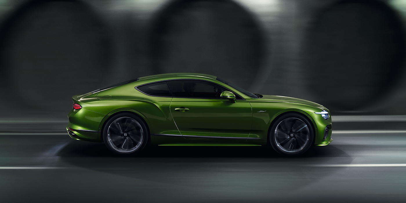 Bentley Monaco Bentley Continental GT coupe in Tourmaline Green paint driving in profile on a dark road